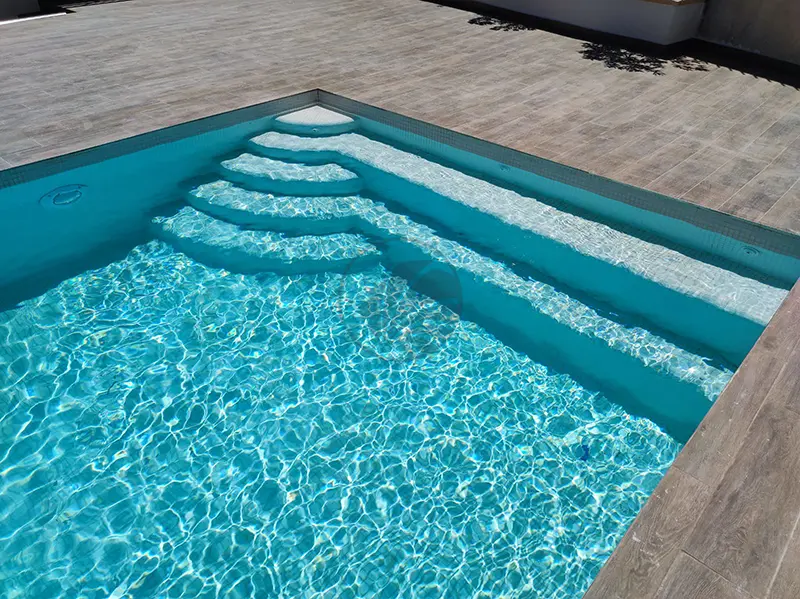 Jolis reflets de l’eau dans une piscine revêtue de mosaïque blanche